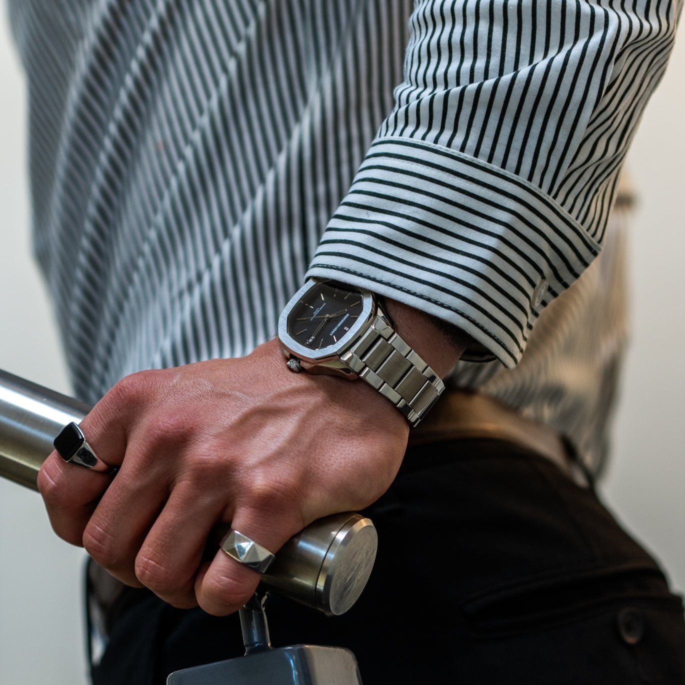 Mand med Fjord ur sort på håndleddet, holder et sølvgelænder.