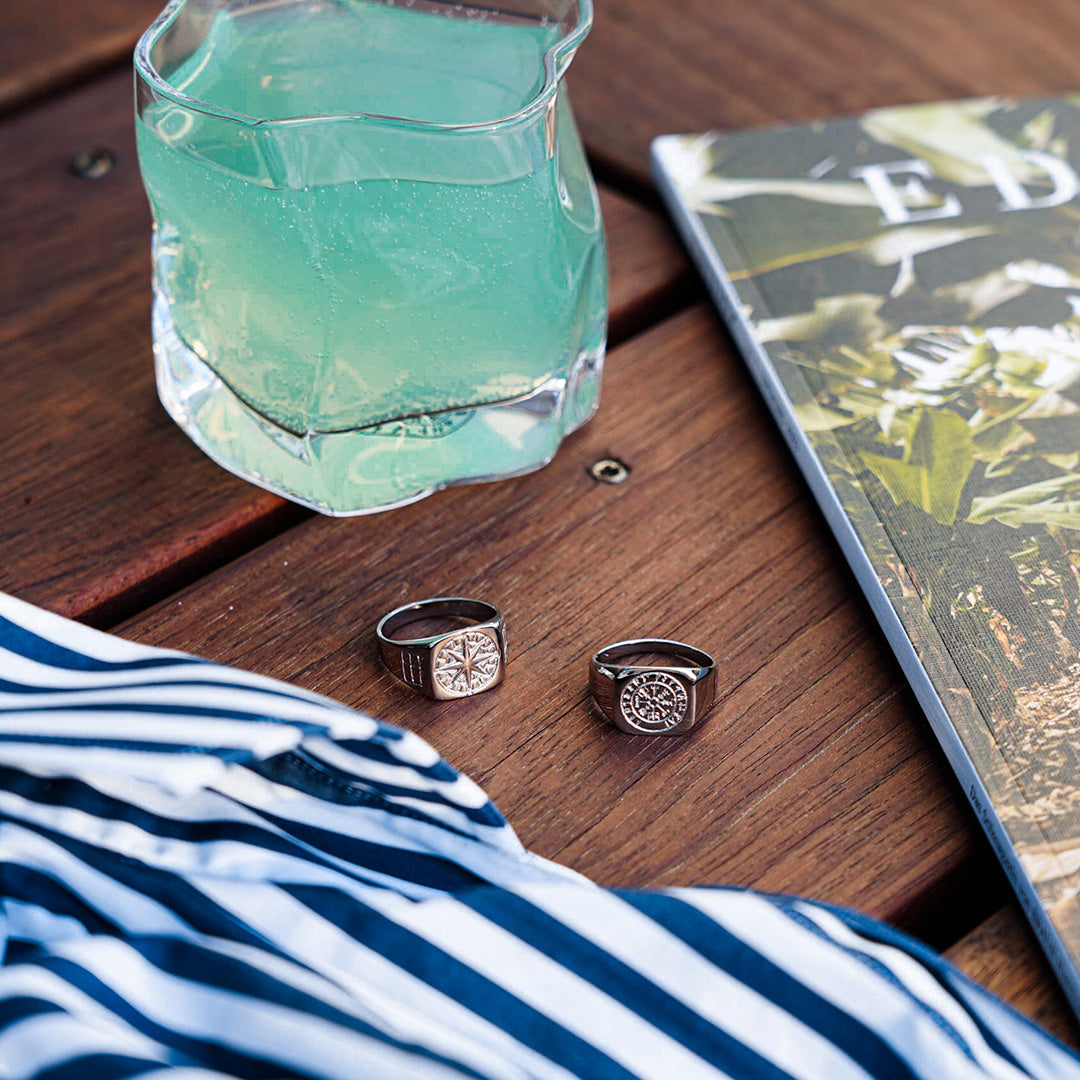 Northern Legacy silver rings on table beside a drink.