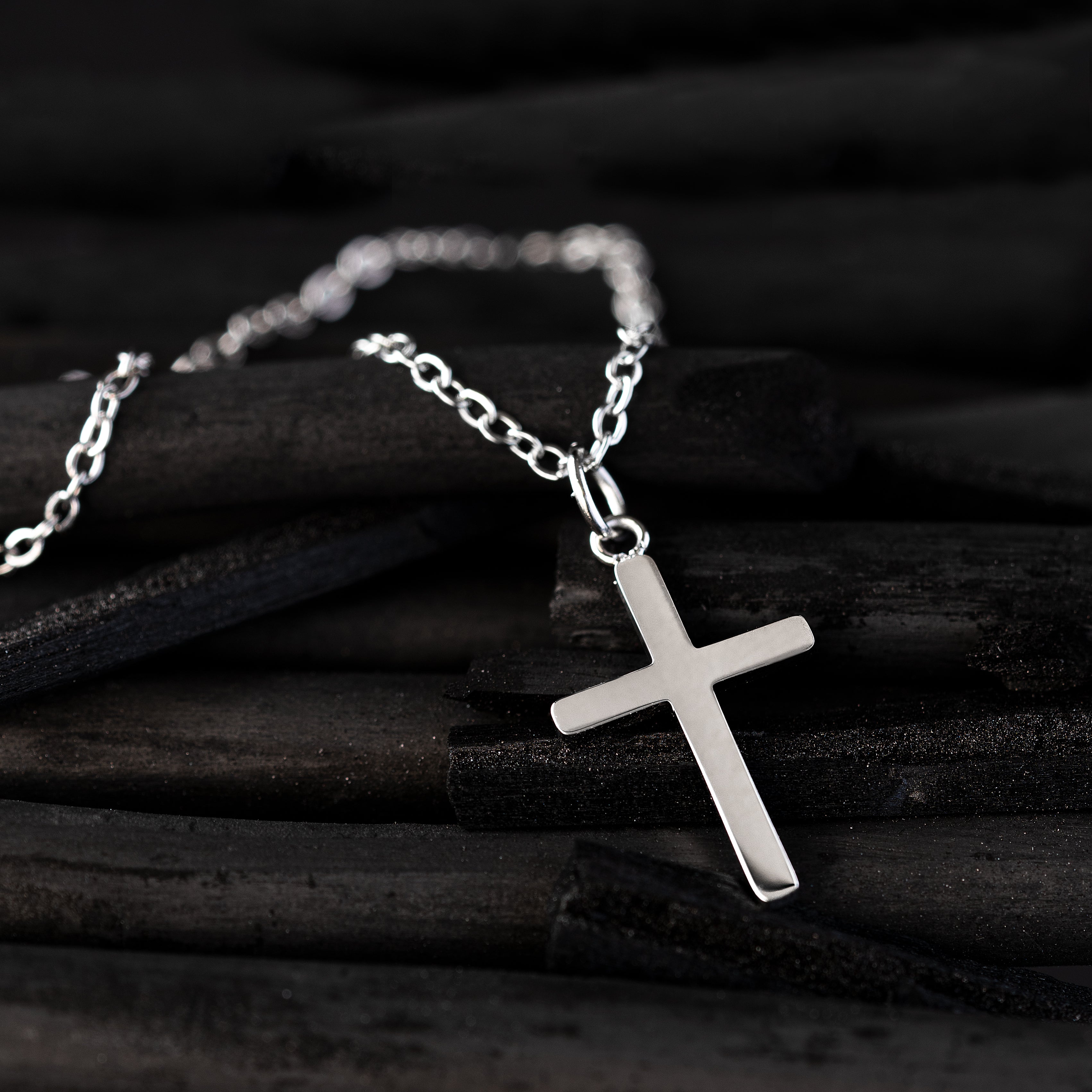 Silver cross chain on black background.